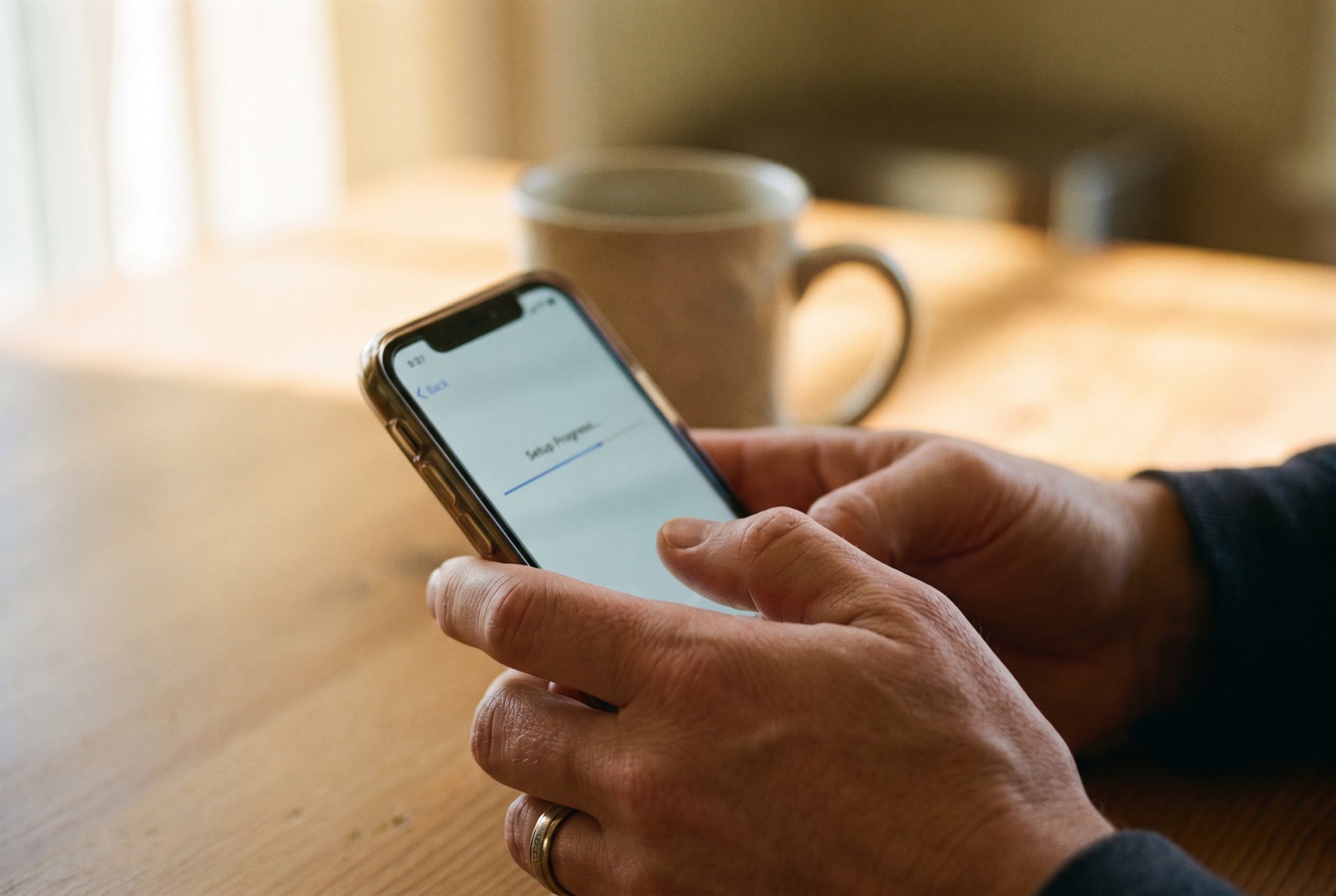 A person's hands setting up a new account on a phone at a kitchen table.